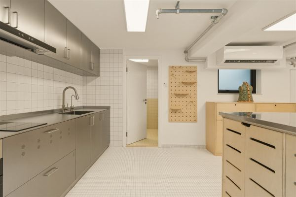 Galley kitchen with stainless steel cabinets, white mosaic floor, and plywood pegboard