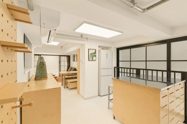 Open kitchen view showing plywood island and green sofa in adjacent room